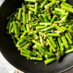 A closer shot of a pan of Sauteed Asparagus, highlighting the bits of garlic in the dish.