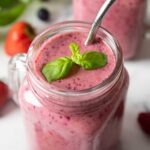 An overhead shot of a mug of Mixed Berry Smoothie, garnished with fresh mint leaves.