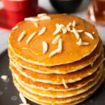 A stack of gluten-free rice flour pancakes, with almond slices on top wiht honey-