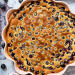 An overhead shot of a freshly-baked blueberry clafoutis, ready for slicing.