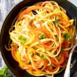 An overhead shot of a serving of pasta with bell peppers, garnished with fresh parsley.