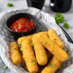 A closer shot of a serving of cheese sticks, served with some catsup.