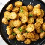 An overhead shot of a plate of roasted baby potatoes cooked in aair fryer, garnished with sea salt.