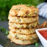 A stack of baked zucchini and potato bites, served with dipping sauce.