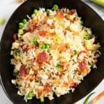 A serving of fried rice with bacon and egg, garnished with chopped spring onions.