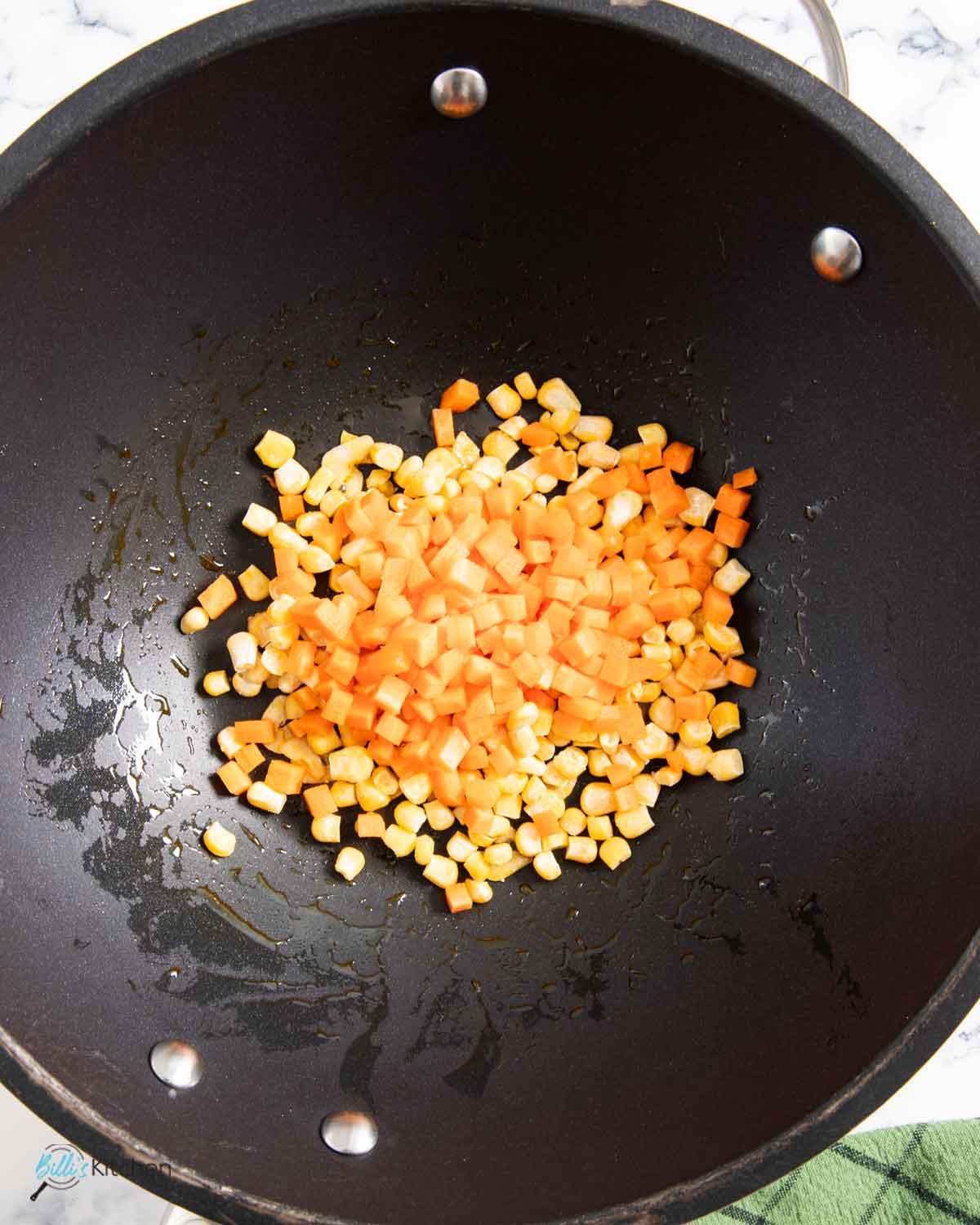 Stir frying corn and carrots before adding the cooked rice and the fried kielbasa.