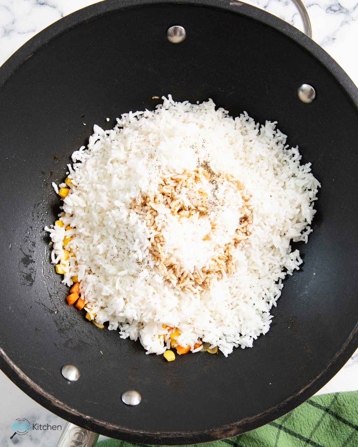 Adding the cooked rice and soy sauce to season the fried rice before adding back the kielbasa.