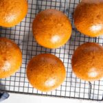 Freshly baked milk bread buns, cooling on a rack.