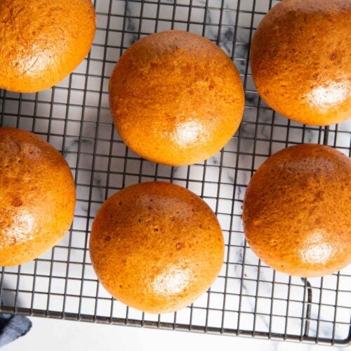 Freshly baked milk bread buns, cooling on a rack.