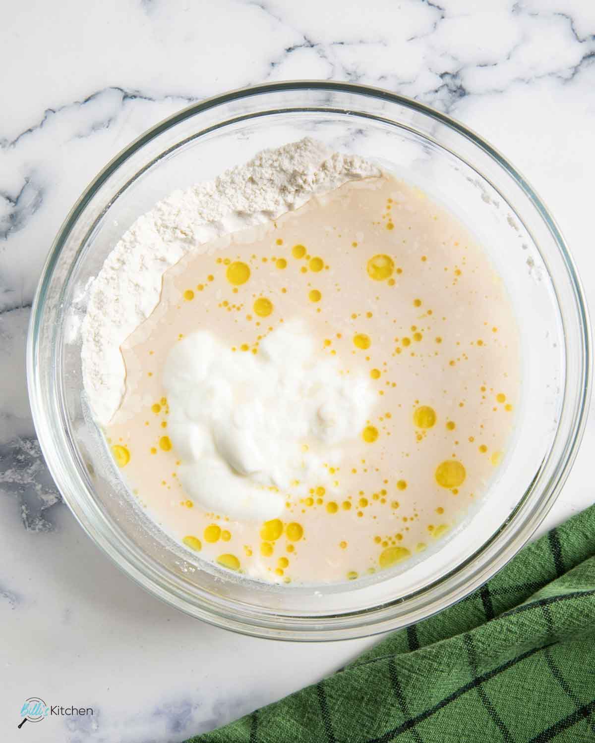 Adding the yogurt, oil and yeast with the dried ingredients to form the dough.
