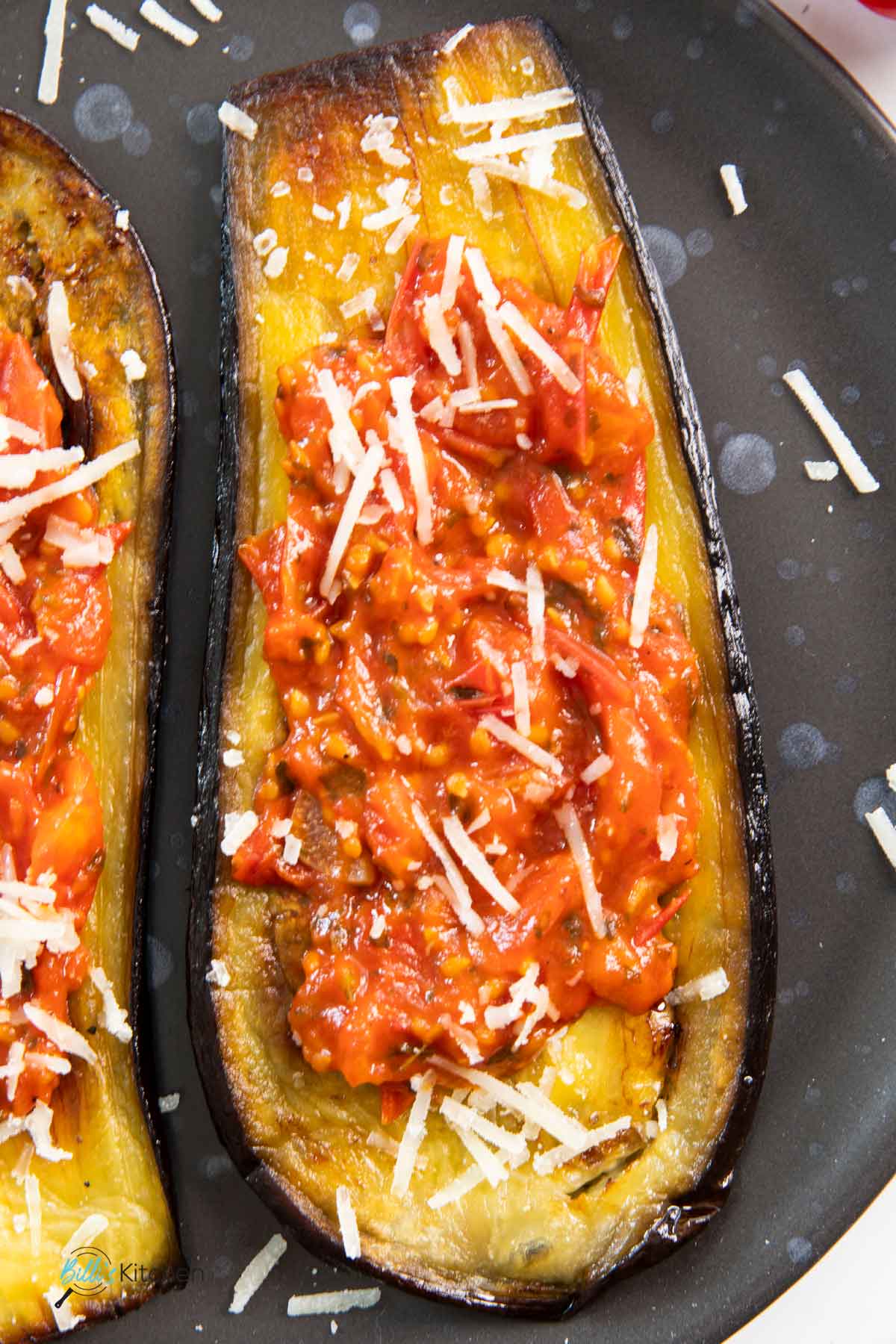 A slice of roasted eggplant with tomatoes, highlighting the soft inside of the eggplant and its browned edges.