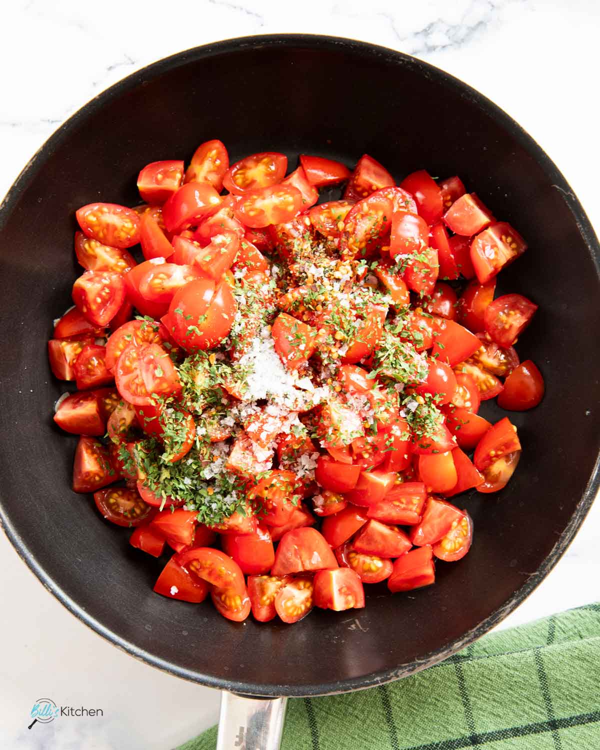 Sautéing fresh tomatoes with dried parsley and seasoning, until the sauce thickens for the eggplants.