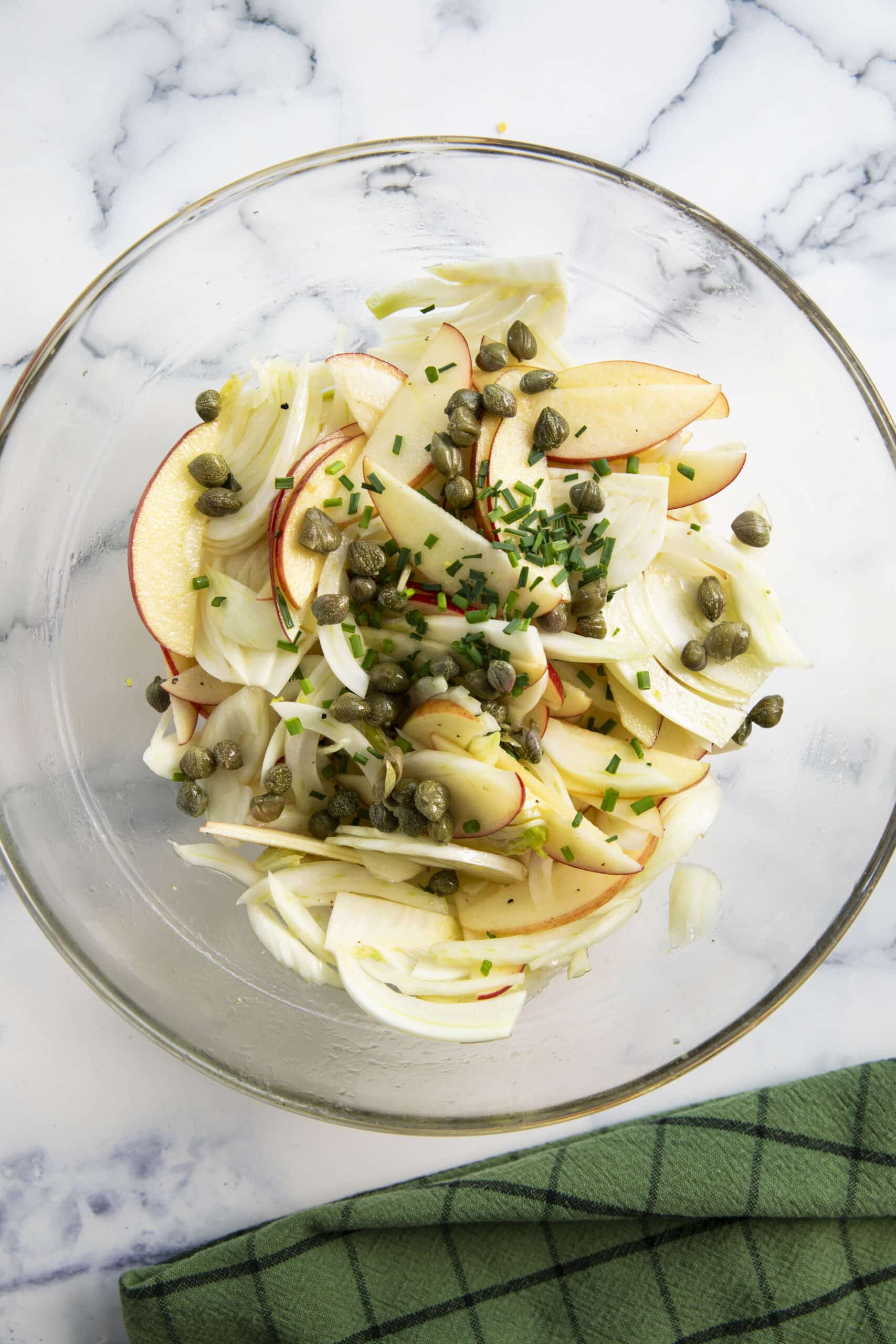 Adding the capers and chives is the last step in preparing fennel with apples for a salad.