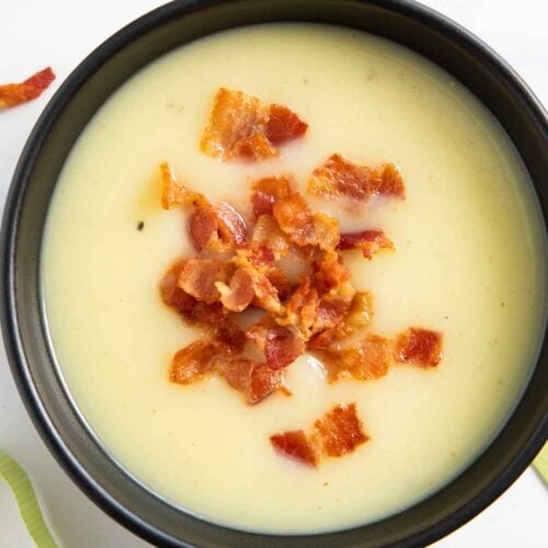 A bowl of potato and leek soup, garnished with crispy bits of bacon.