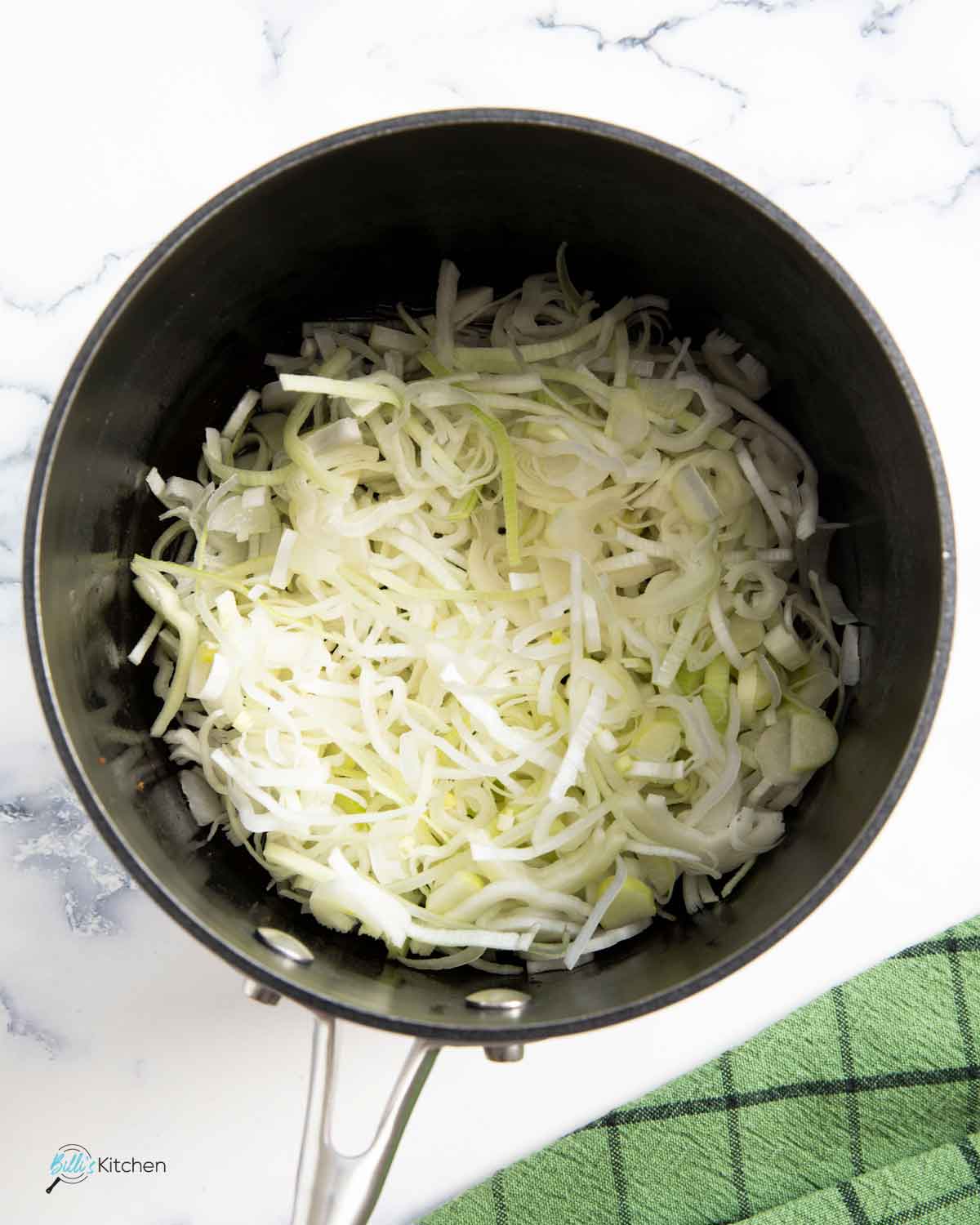 Sautéing thin slices of leeks using the oil from the frying of the bacon, to add more flavor to the soup.