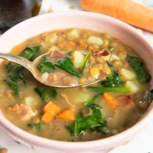 A closer shot of a spoonful of bacon and lentil soup, highlighting the texture of the soup.