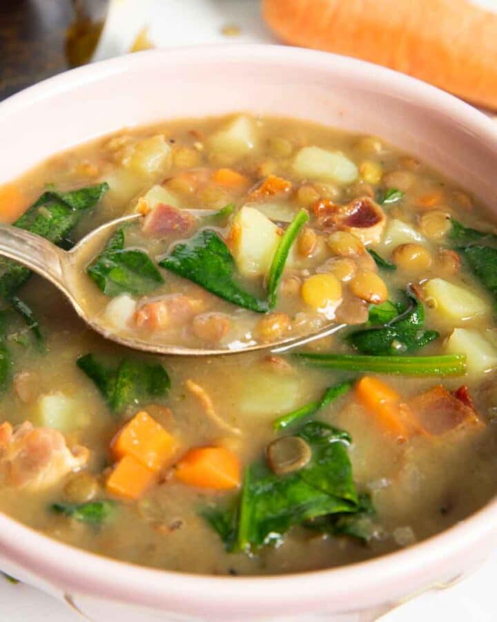 A closer shot of a spoonful of bacon and lentil soup, highlighting the texture of the soup.