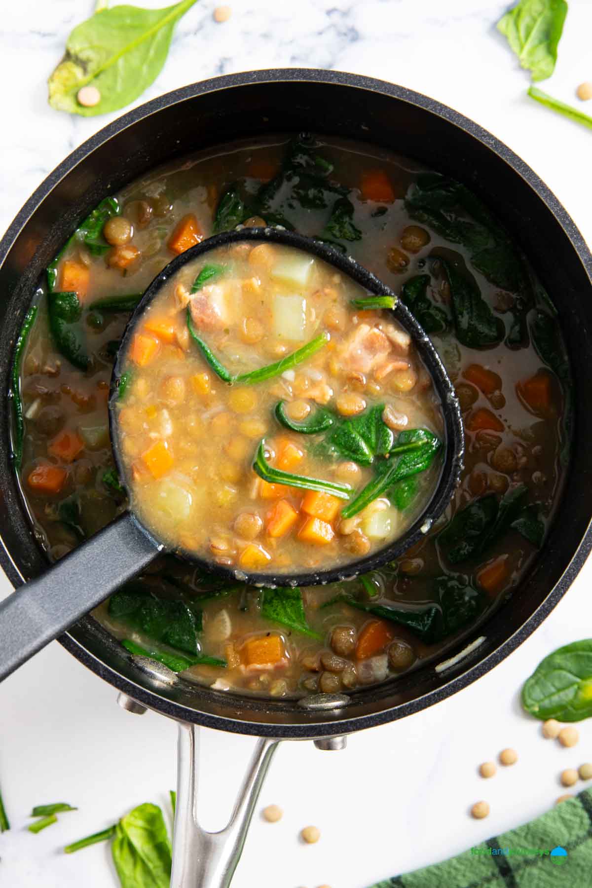 A ladle of homemade soup of bacon and lentils, ready for serving.