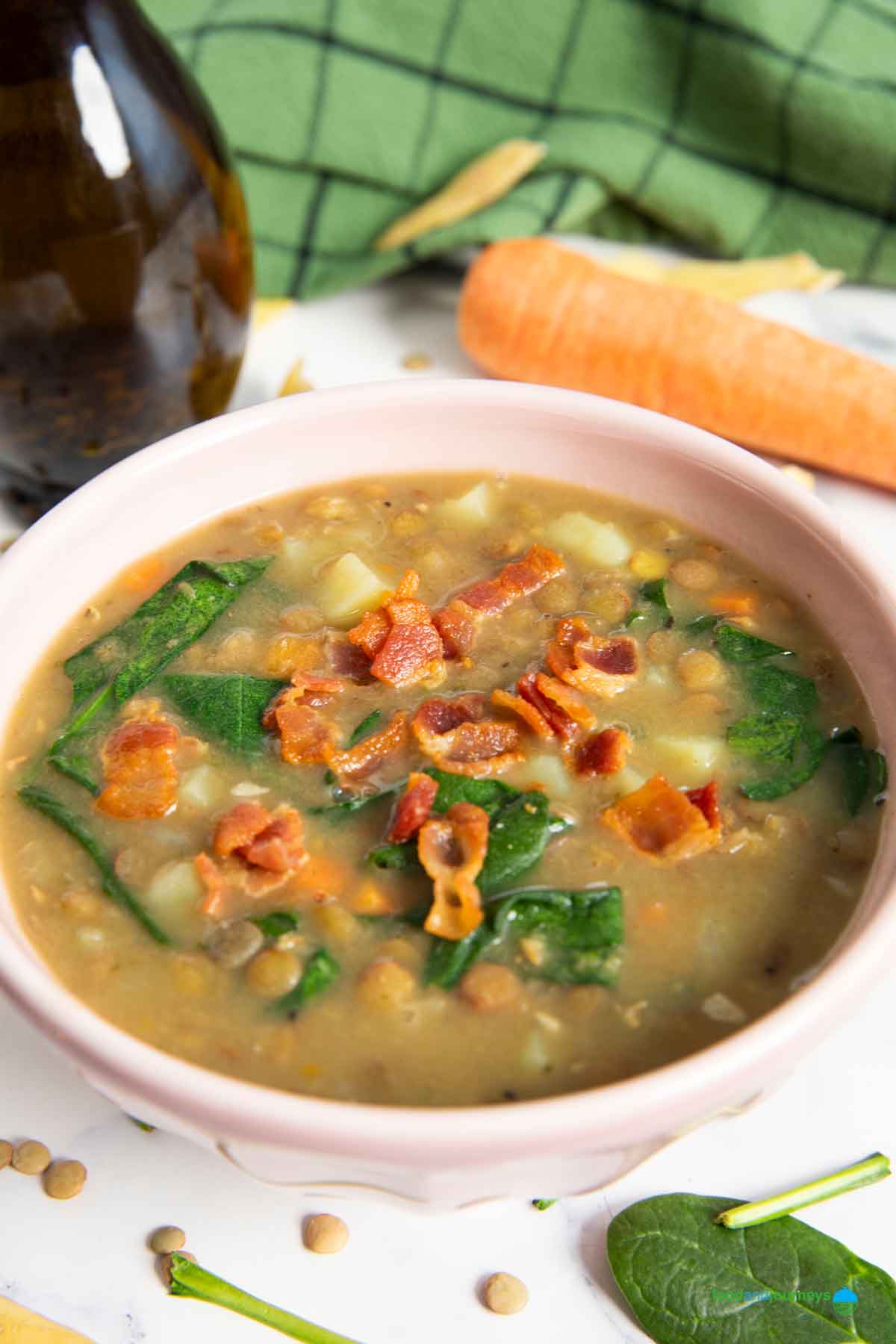A bowl of homemade lentil and bacon soup, garnished with fried bacon.