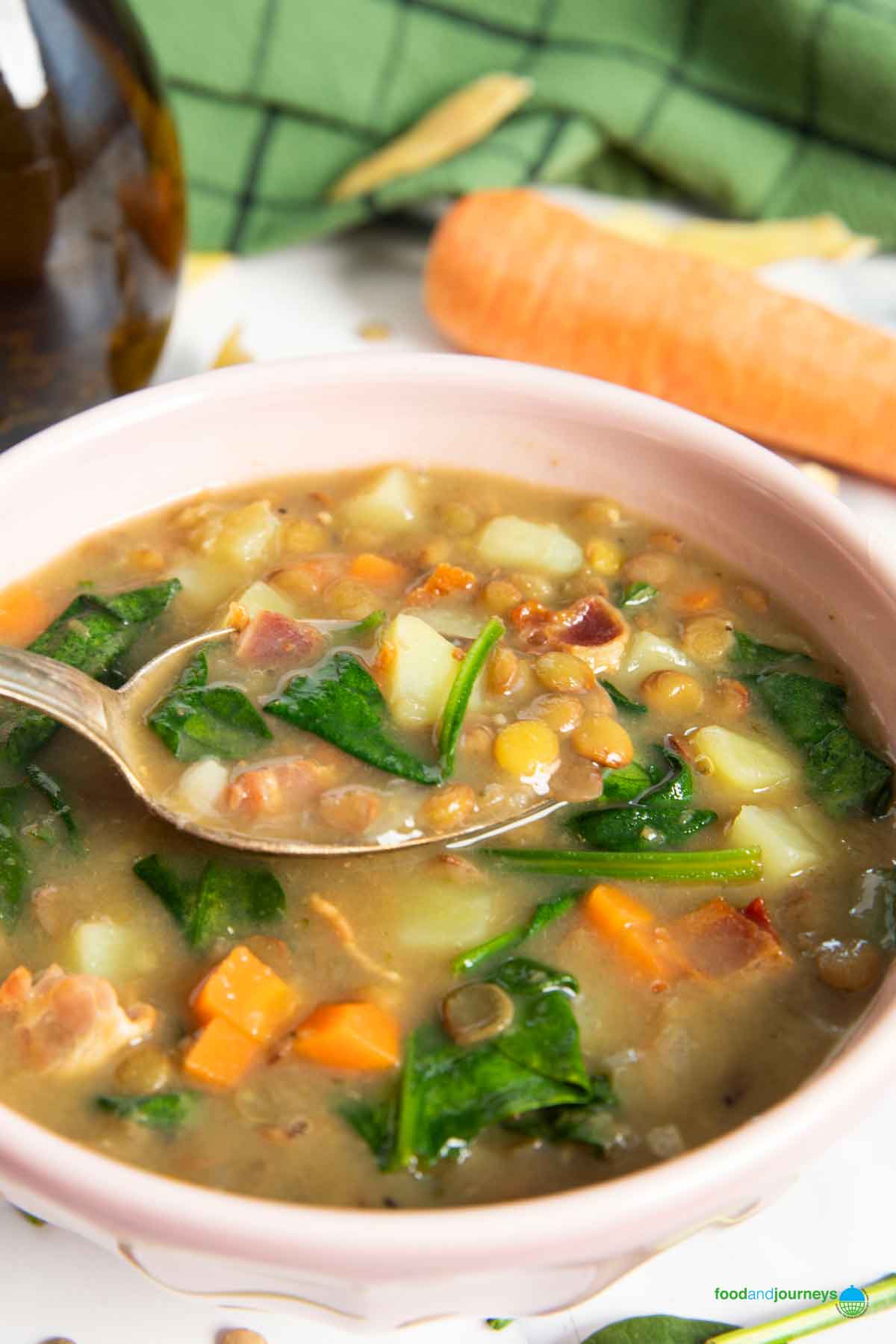 A closer shot of a spoonful of lentil and bacon soup, showing the thickness of the soup.