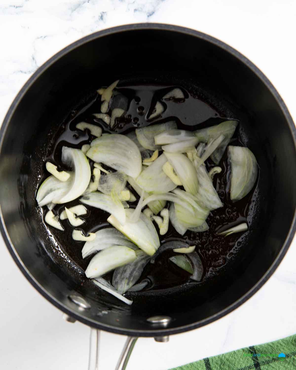 Sautéing garlic and onions is the first step in preparing the soup base for lentils and bacon.