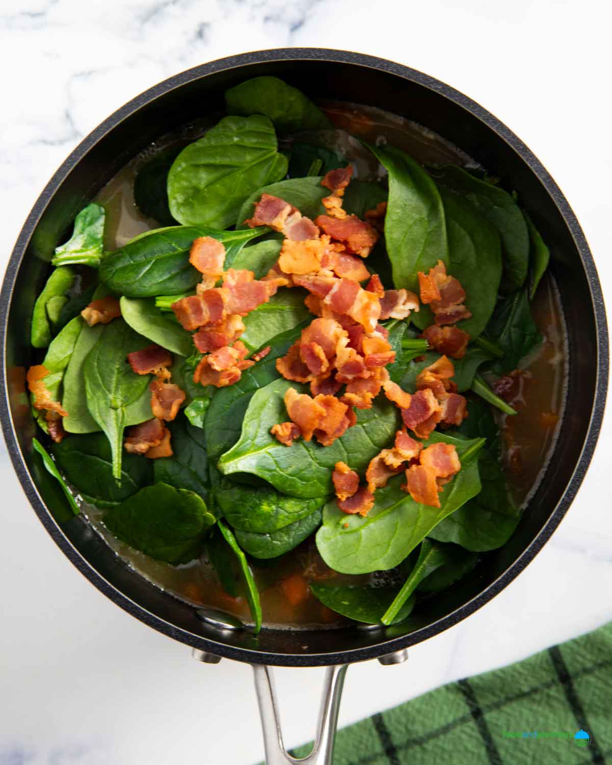 Adding the spinach and fried bacon is the last step for preparing this homemade soup.
